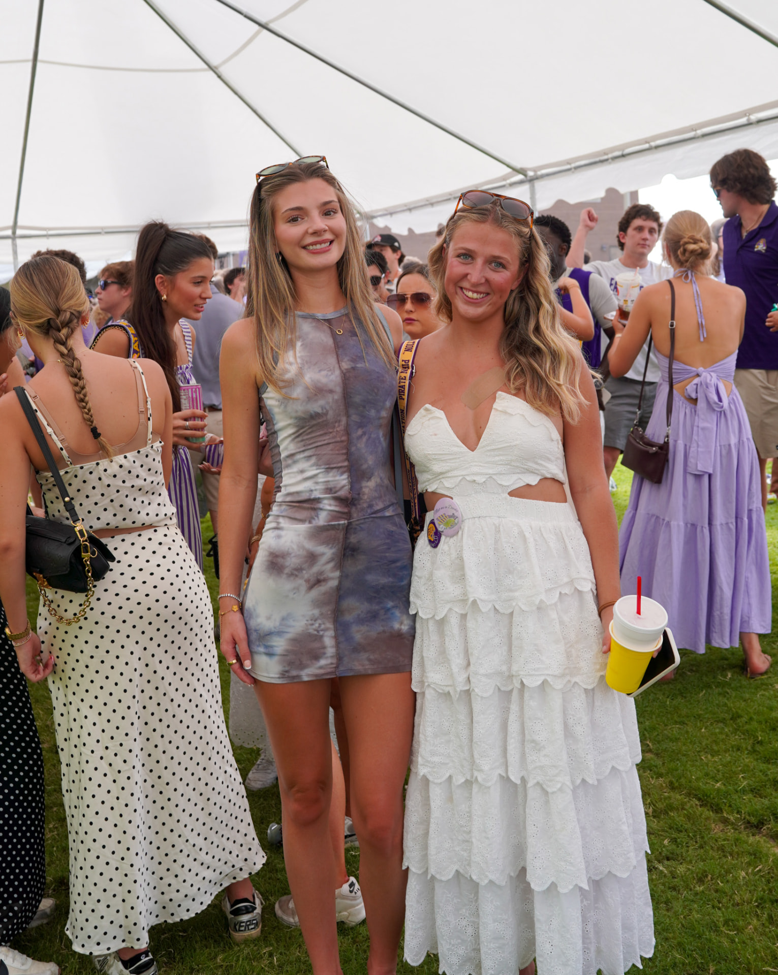 Two women smiling beneath an event tent
